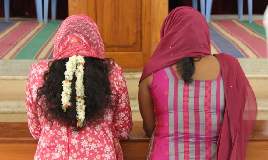 Intialaiset naiset rukoilevat värikkäissä vaatteissa