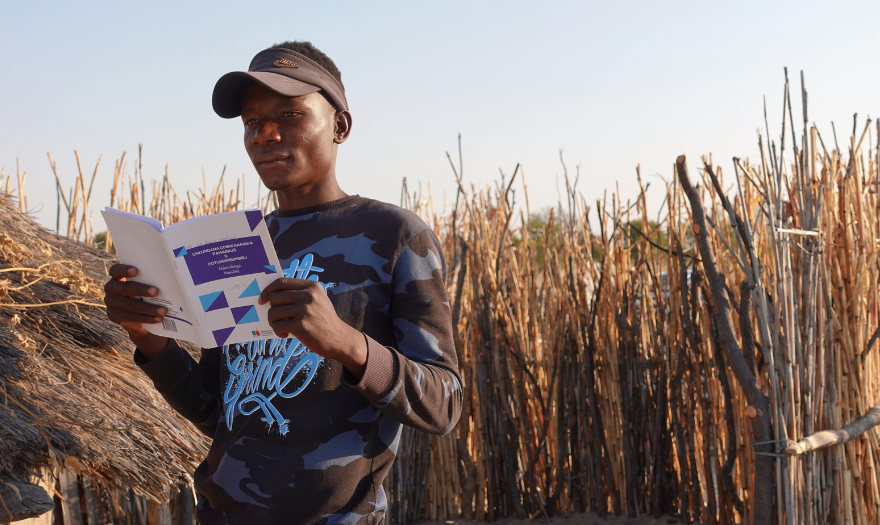 Nuorukainen lukee Raamattua kotinsa edessä Namibiassa