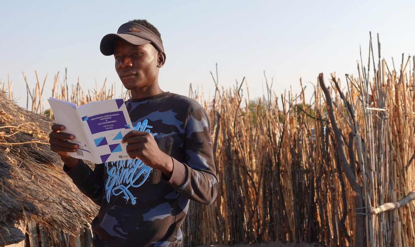 Namibialainen nuorukainen lukee Raamattua kotinsa edessä