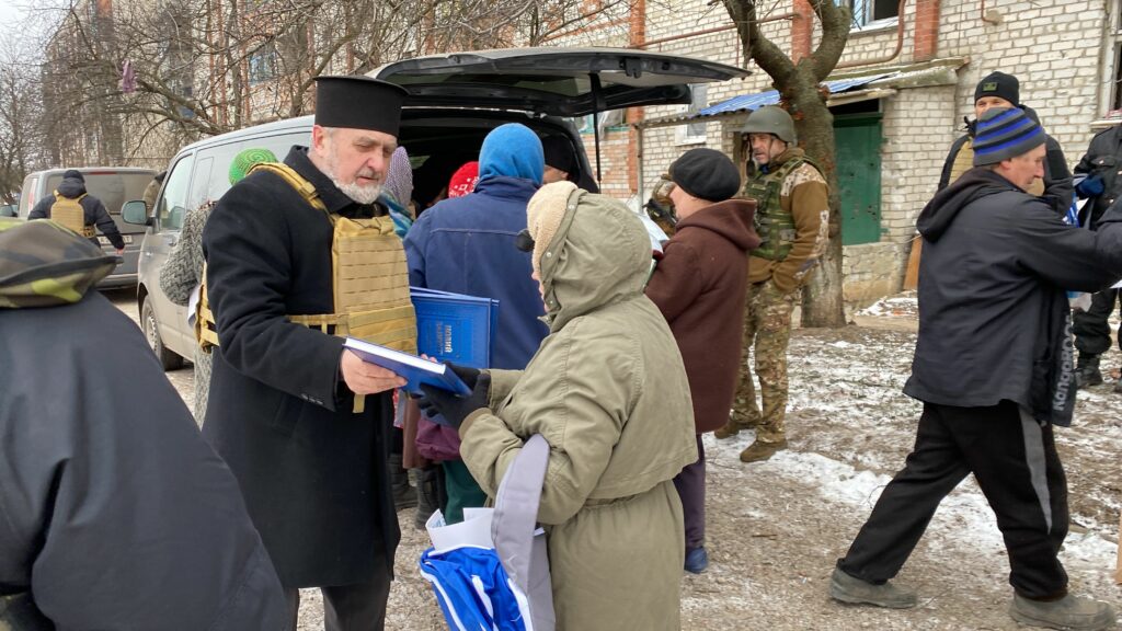 Pappi jakaa Raamattuja joukolle ihmisiä Ukrainassa