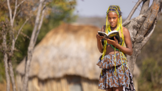 Angolalainen tyttö lukee Raamattua afrikkalaisessa kylässä