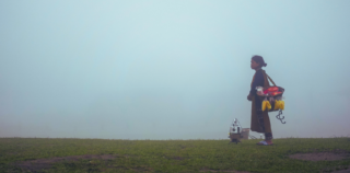 Koillis-Intialainen nainen seisoo vuoren laella sumuisen maiseman edessä.