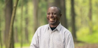 Mies hymyilee leveästi metsässä