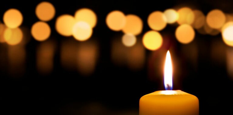 yksi kynttilä etualalla, takana monta valoa