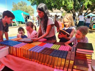 Paljon lapsia ja yksi aikuinen nainen ulkotapahtumassa kirjanmyyntipisteellä Israelissa