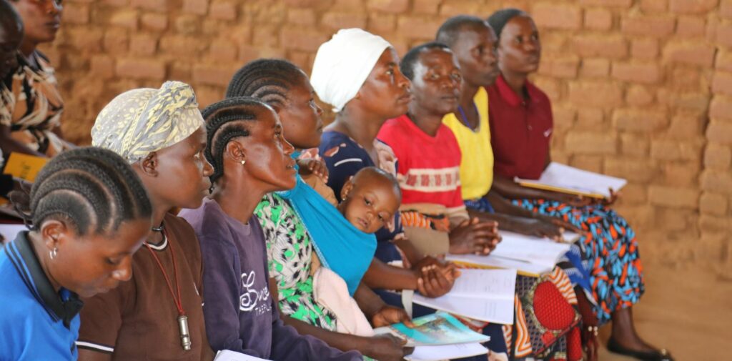 Naisia lukutaitoluokassa vihot sylissään