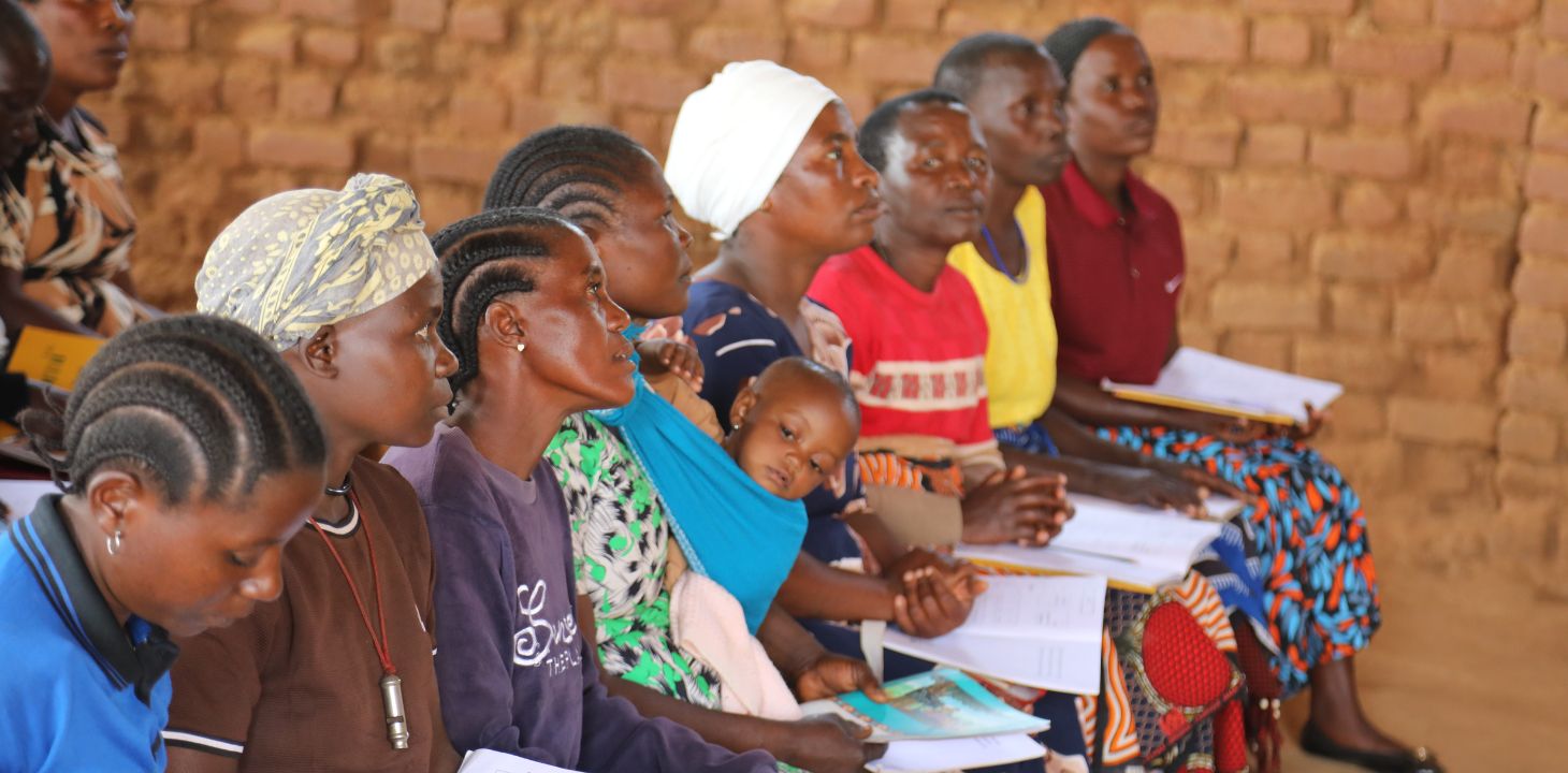 Naisia lukutaitoluokassa vihot sylissään