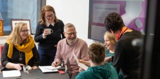 joukko ihmisiä nauramassa toimistolla