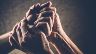 Seepianvärinen tyylikäs kuva kahden eri ikäisen ihmisen käsistä, joista toiset ikäänkuin kannattelevat toisen henkilön kättä.