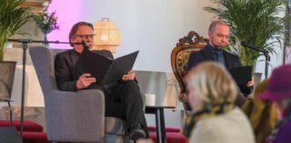 Kaksi miestä istumassa nojatuolissa kirkossa