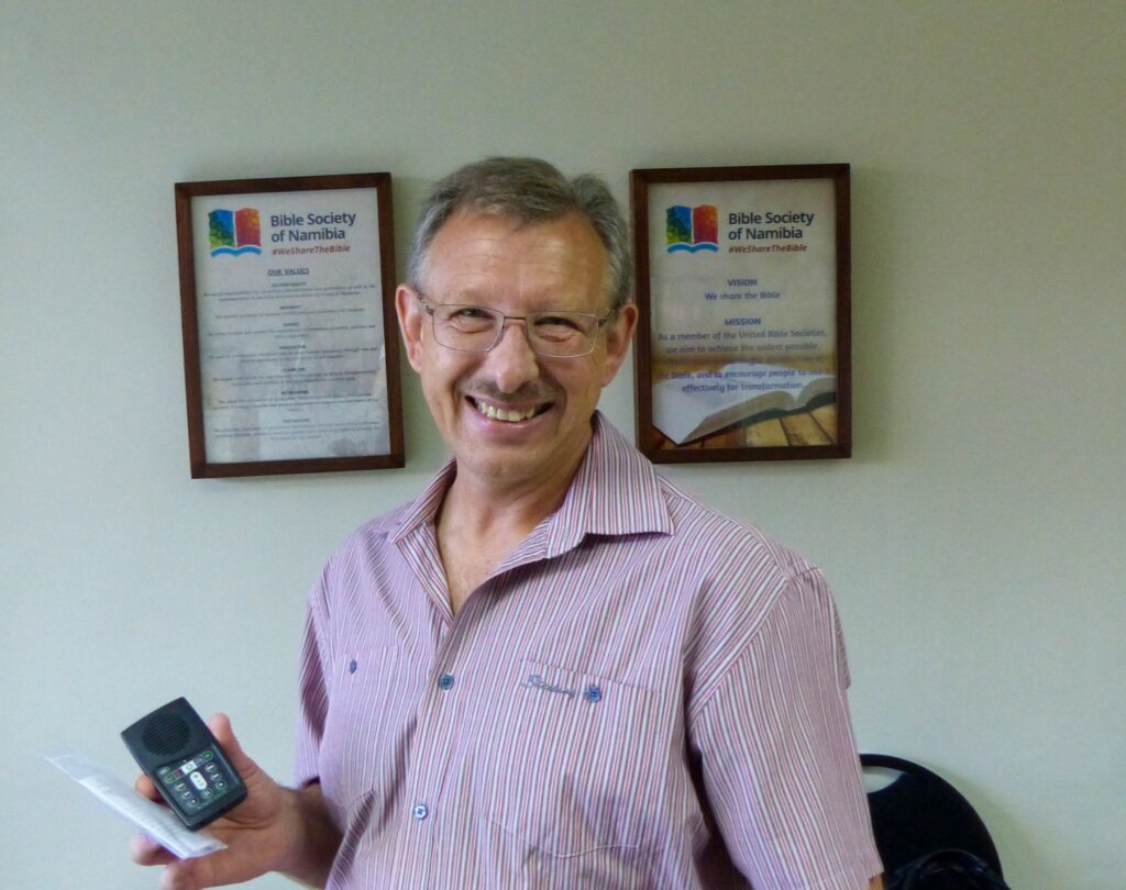 Namibian Pipliaseuran pääsihteeri Schalk Botha poseeraa toimistossaan iloisesti hymyillen